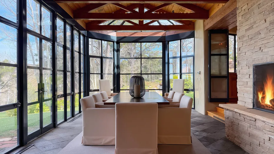The dining room features a table in a room with glass all around.