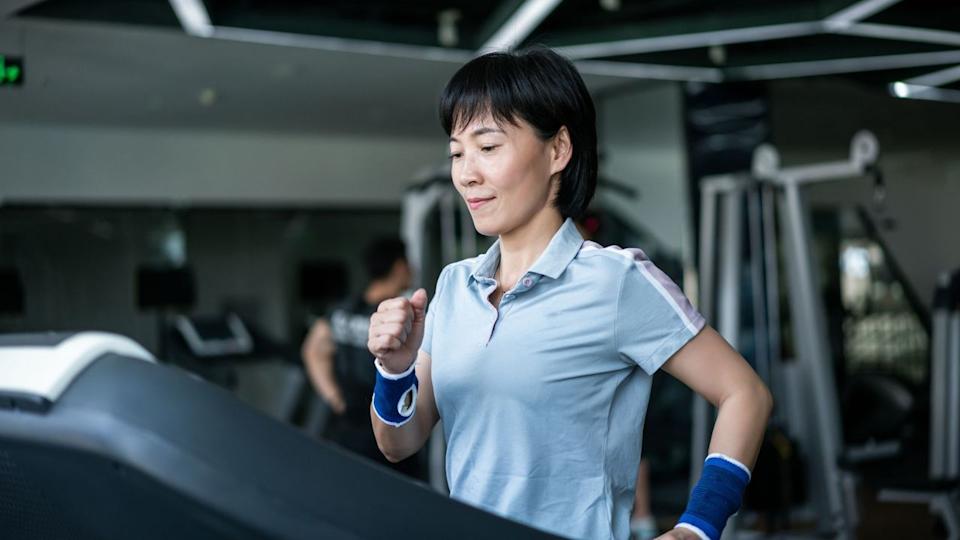  Woman doing incline walking workout at a gym. 