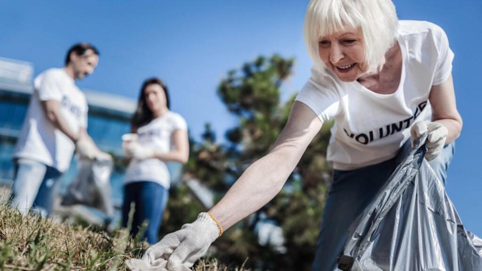Happy smiling old aged woman taking litter as a volunteer