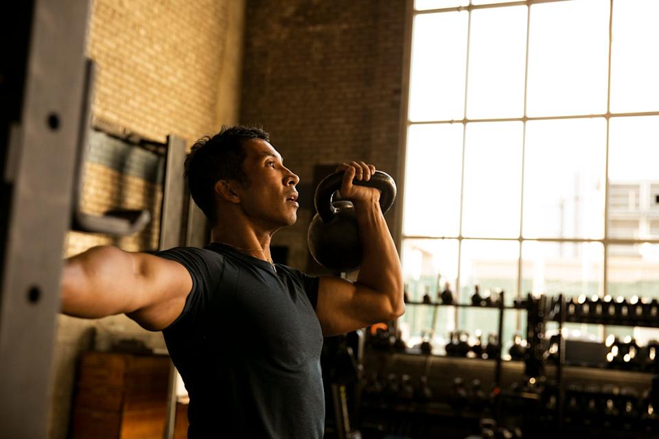 Person performing a kettlebell exercise in a gym setting