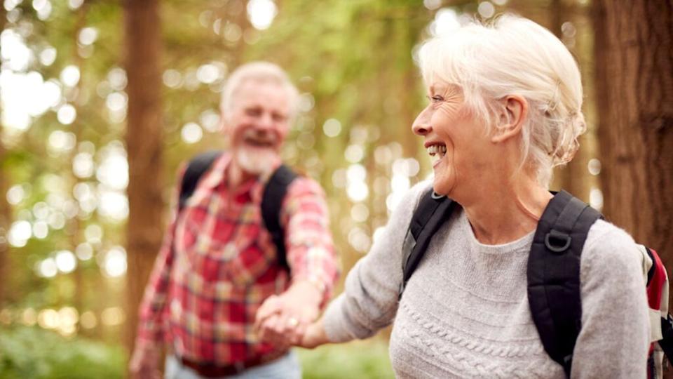 Loving Retired Senior Couple Holding Hands Hiking in forest