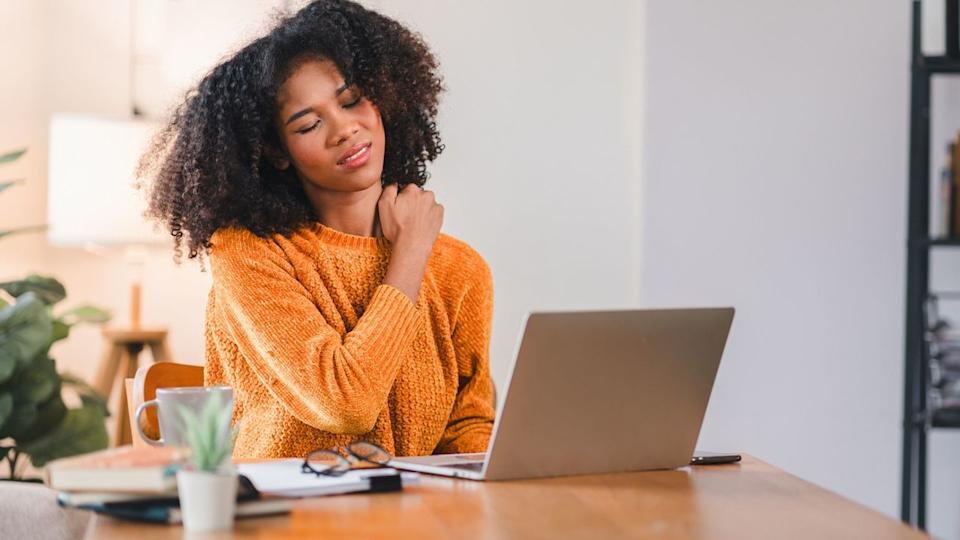  Woman works at desk and hold shoulder in pain. 
