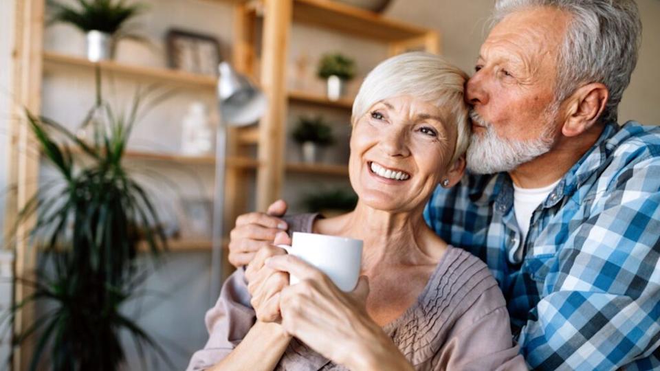 retired happy couple kiss coffee living room