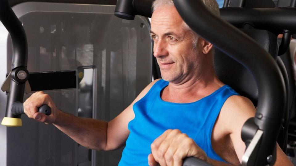 Man Using Weights Machine In Gym doing chest press