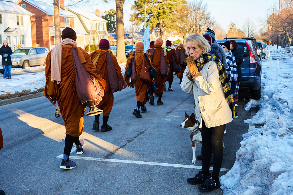 A local resident looks on as Buddhist monks participate in a "Walk for Peace" in Richmond,