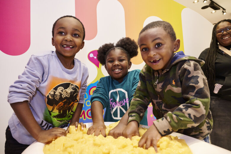 children with hands in yellow slime vat
