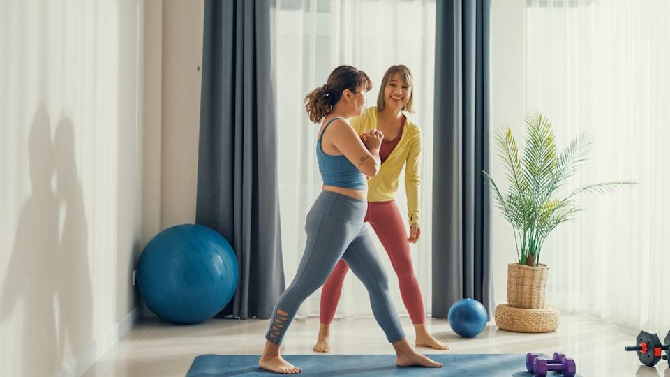  Two women in activewear surrounded by exercise equipment. 