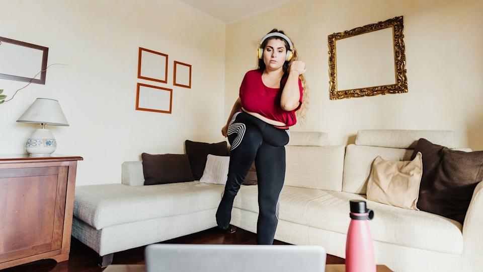  Woman exercises in living room in front of a laptop. 