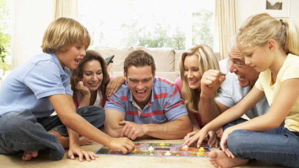 Family Playing Board Game At Home With Grandparents Watching