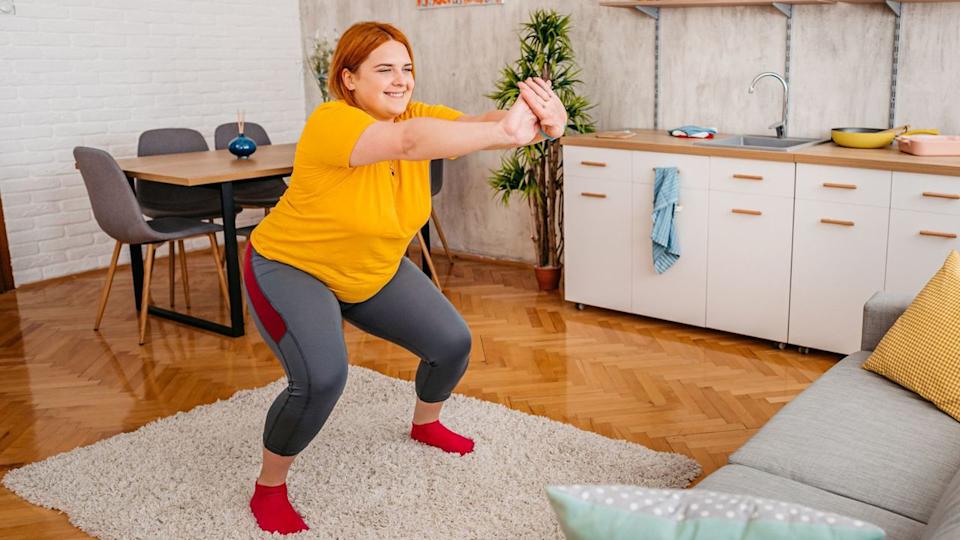  Woman does squat exercise at home . 