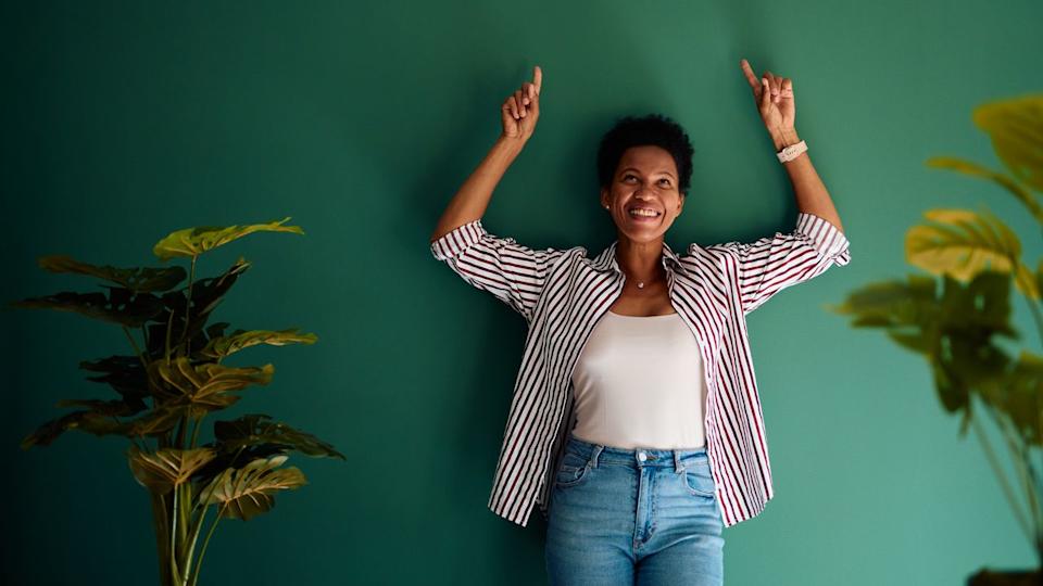  Woman with her back against a wall and arms raised. 