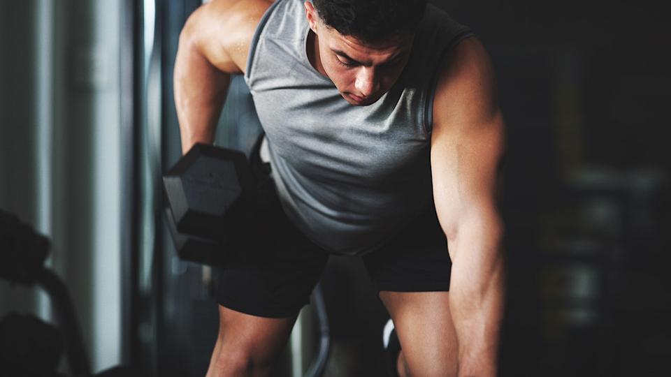 Shot of a sporty young man exercising with a dumbbell at the gym
