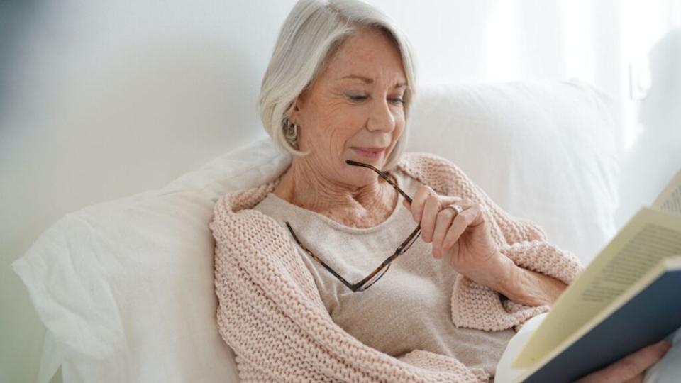 Beautiful senior woman relaxing in bed reading