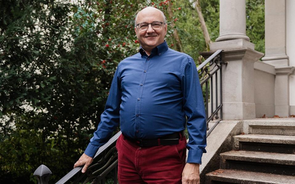 Smiling man on an outdoor stairwell resting one of his hands on a railing