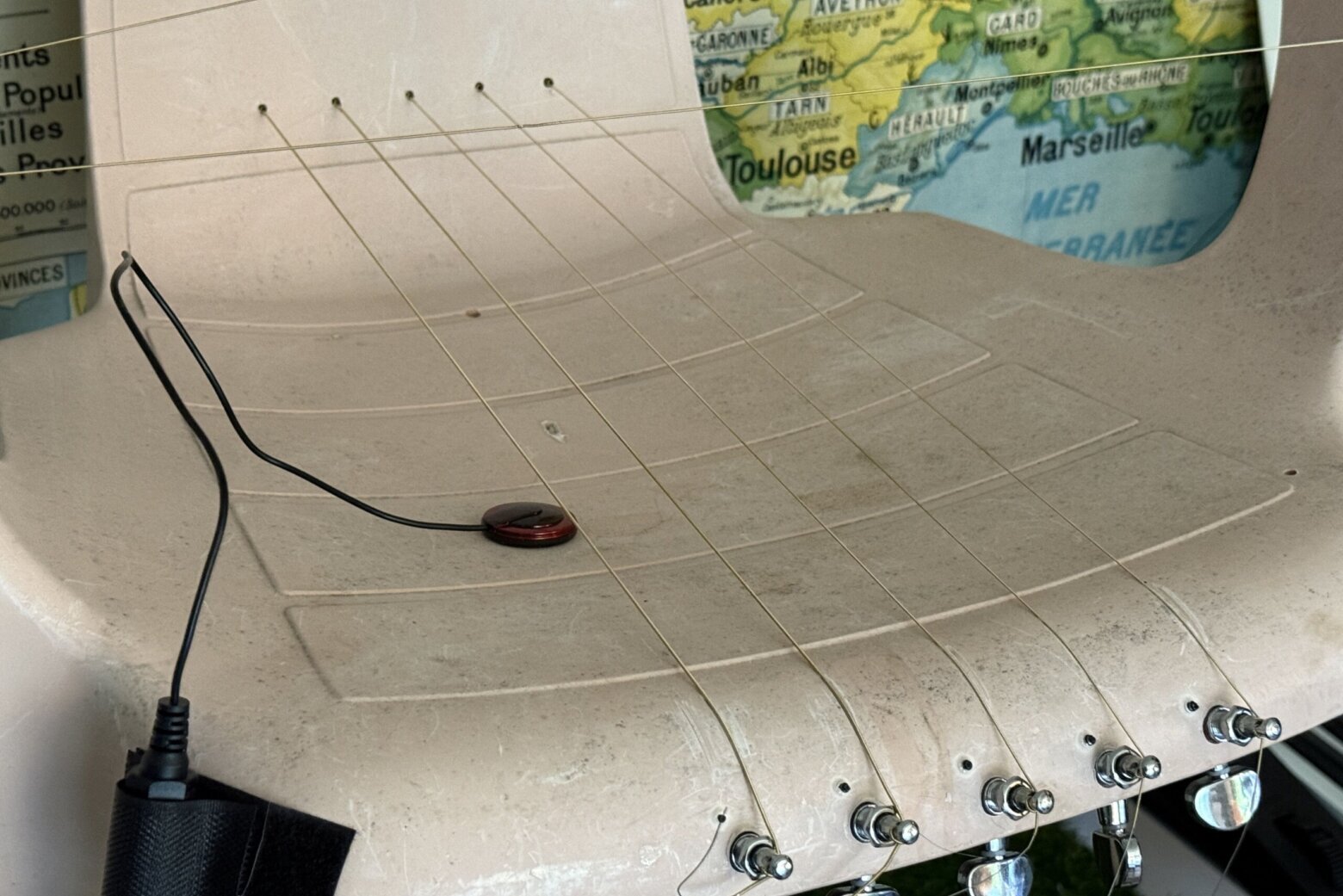 close up of guitar strings in a monobloc chair to create an artisitc instrument